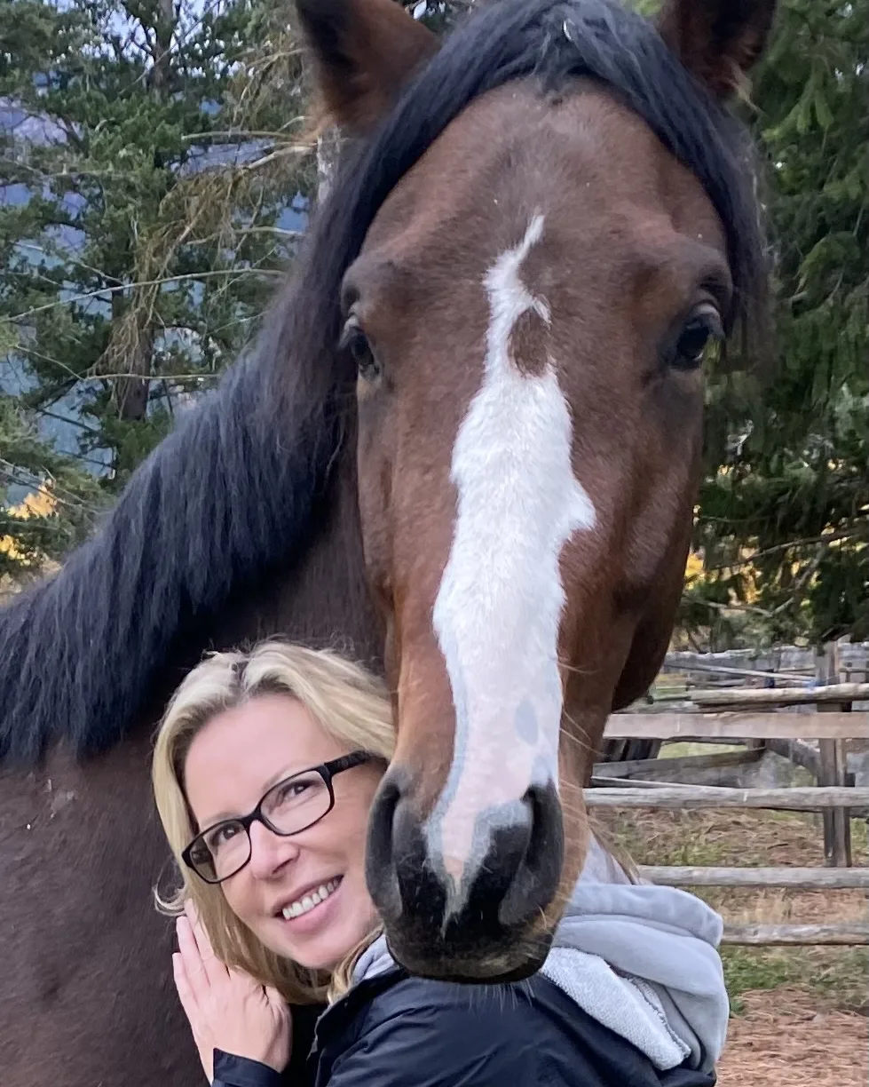 The owner smiling, cheek to cheek with a bay horse with a white blaze
